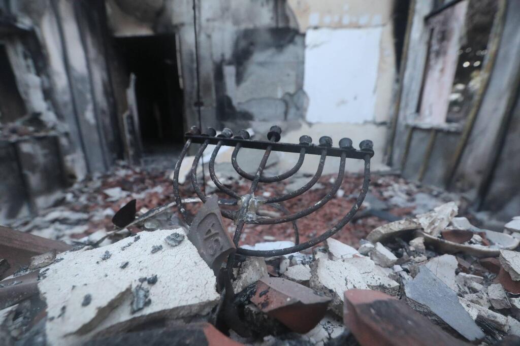 A charred menorah among the ruins of a house in Kibbutz Be'eri.